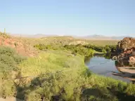 Verde River lined with green reeds and rocky banks where Sheep Bridge Hot Springs hides