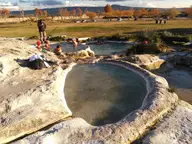 Round travertine rimmed thermal pool with milky water at Piscine Carletti near Viterbo