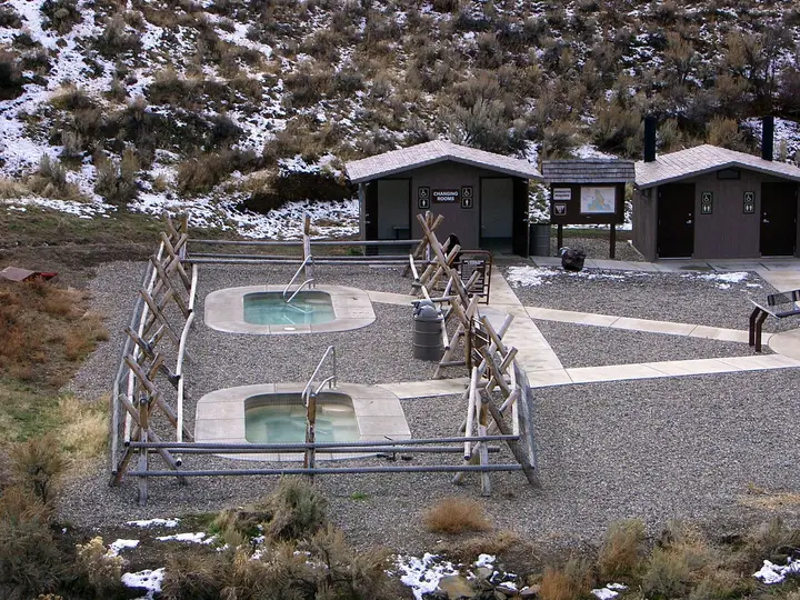 Two concrete soaking pools inside wooden rail fences beside changing rooms at Sharkey Hot Springs