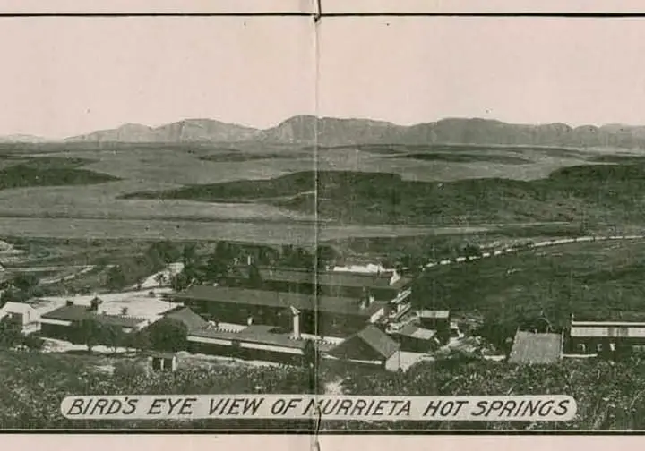 Historic bird's eye view of Murrieta Hot Springs resort buildings below rolling hills and mountains