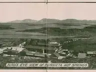 Historic bird's eye view of Murrieta Hot Springs resort buildings below rolling hills and mountains