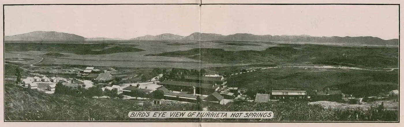 Historic bird's eye view of Murrieta Hot Springs resort buildings below rolling hills and mountains