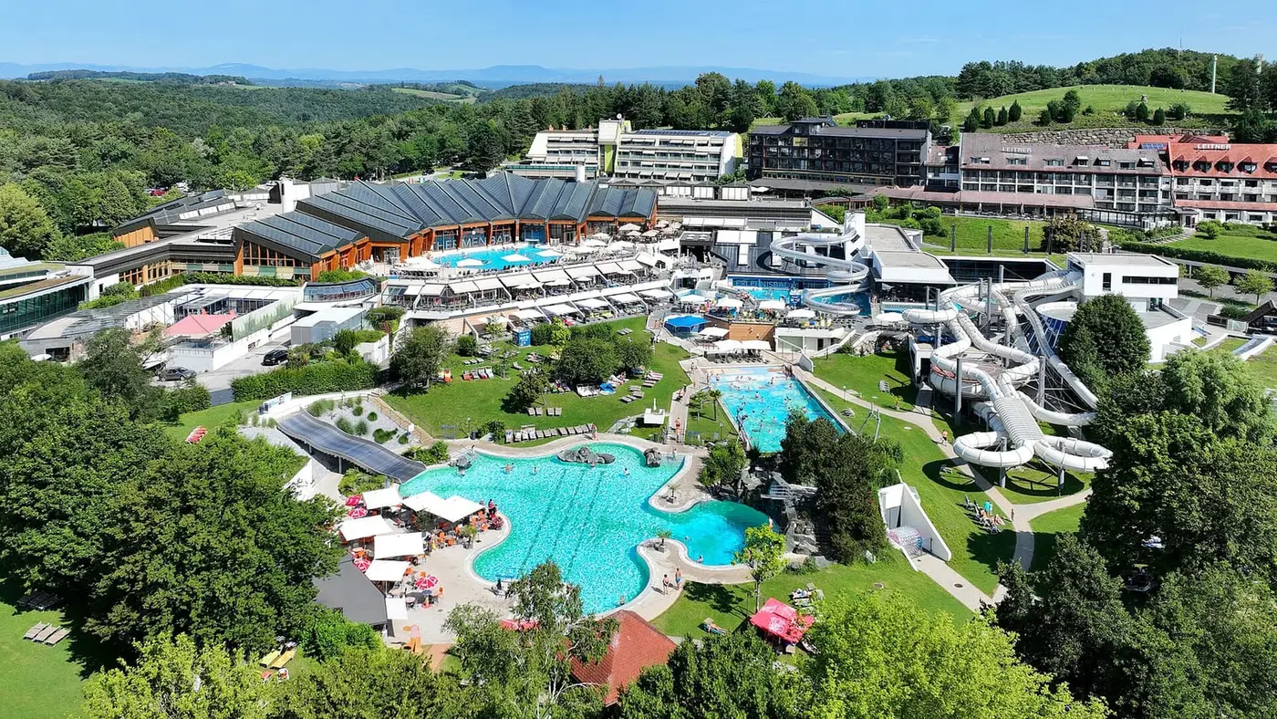 Aerial view of Thermenresort Loipersdorf with turquoise outdoor pools, water slides and green hills