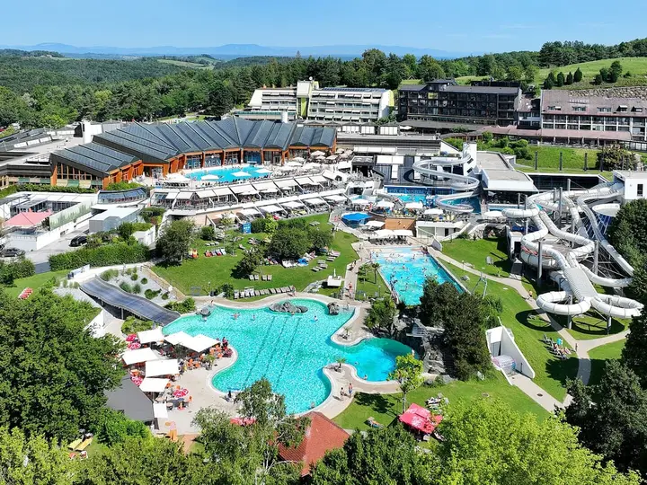 Aerial view of Thermenresort Loipersdorf with turquoise outdoor pools, water slides and green hills
