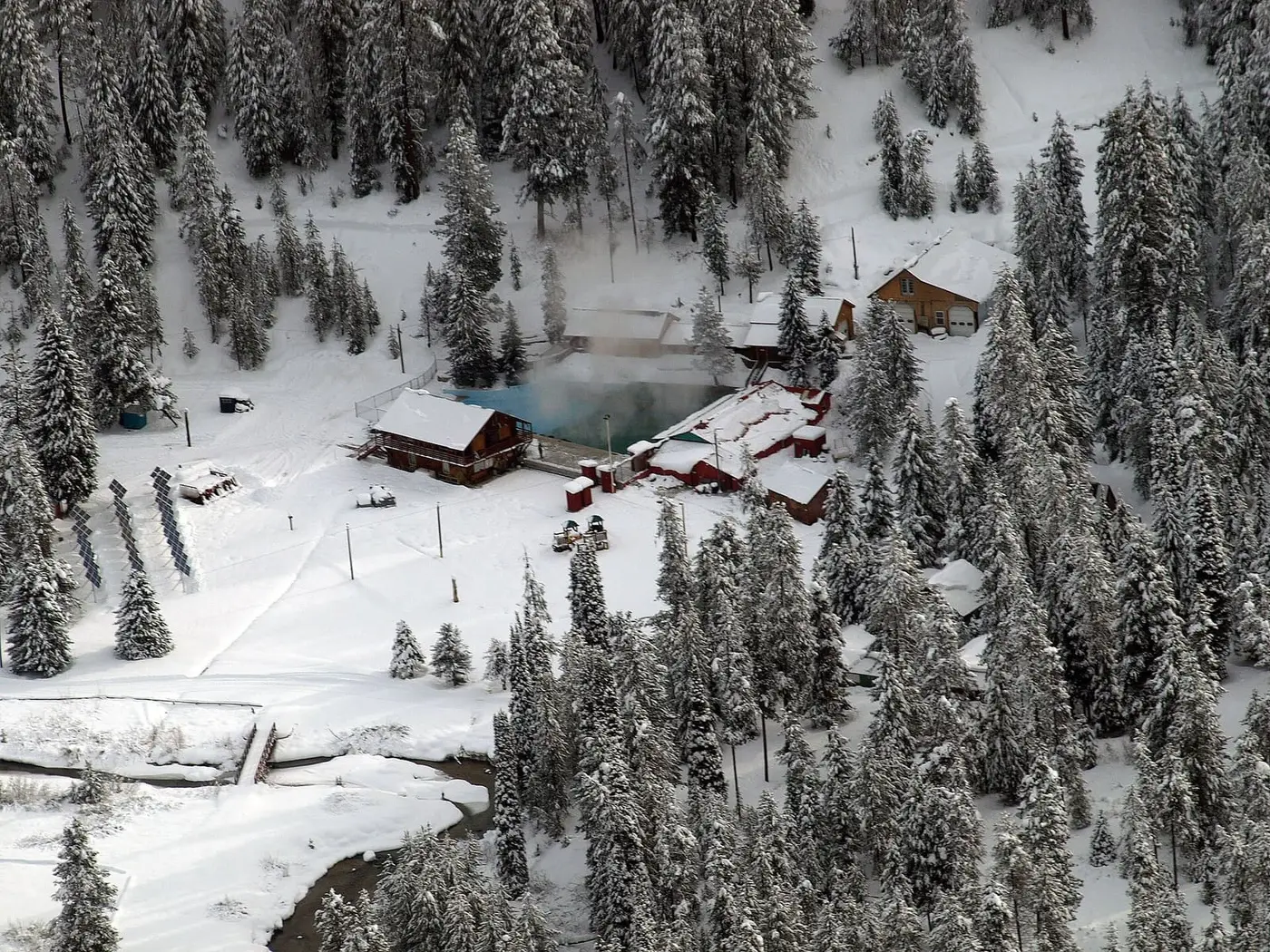 Silver Creek Plunge in winter, its steaming pool among snowy cabins and fir forest