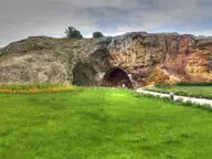 Weathered rock outcrop with a cave opening above a green lawn in Kırşehir's Terme quarter