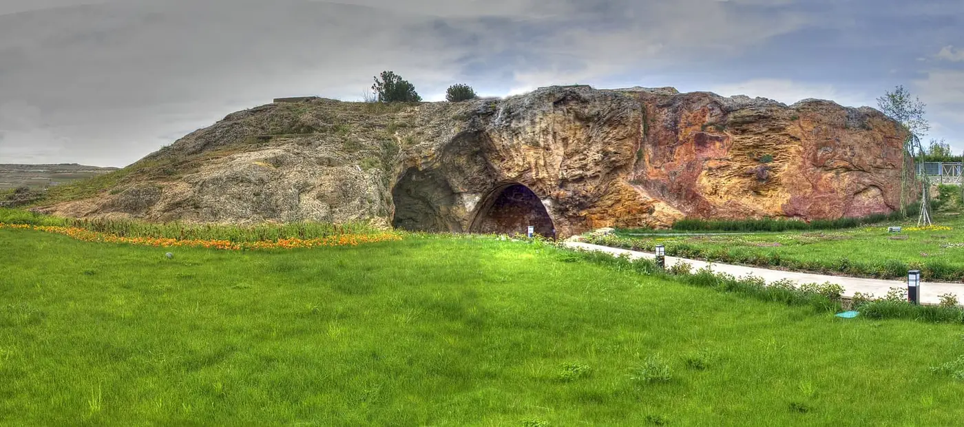 Weathered rock outcrop with a cave opening above a green lawn in Kırşehir's Terme quarter