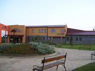 Orange and stone entrance building of the Vulkán thermal bath in Celldömölk with a garden