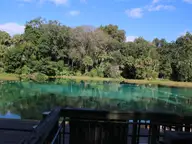Clear turquoise swimming area at Rainbow Springs headspring under blue sky and green forest