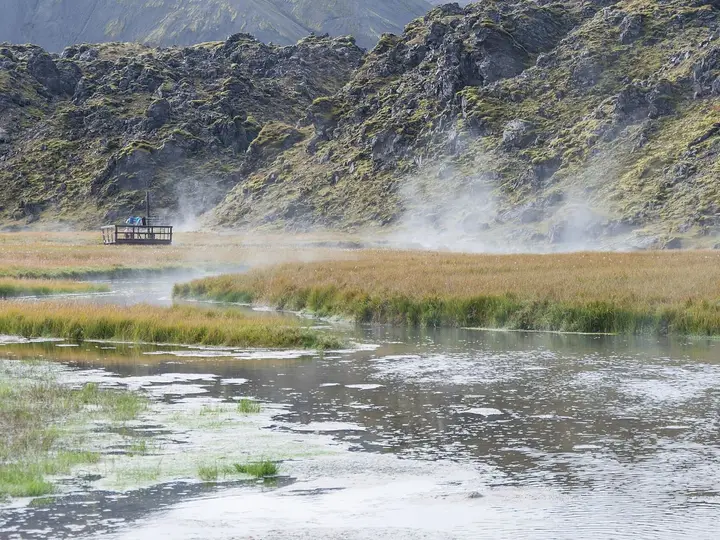 Steam rising over the warm stream at the edge of the Laugahraun lava field in Landmannalaugar