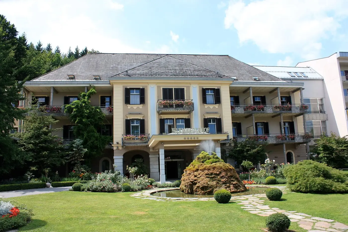Historic Warmbaderhof spa hotel with balconies and a manicured garden in Warmbad Villach