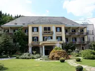 Historic Warmbaderhof spa hotel with balconies and a manicured garden in Warmbad Villach