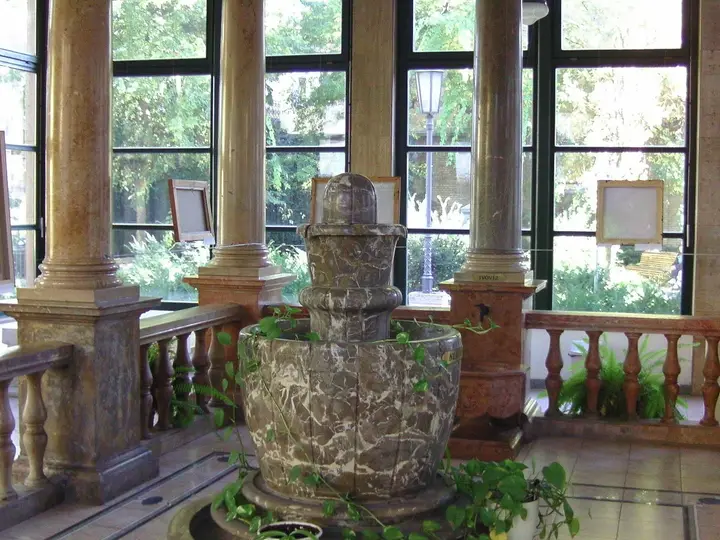 Stone thermal well fountain inside a columned pavilion at the Lukács Thermal Bath entrance