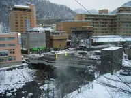 Steam rising from the Toyohira River beneath snowy hotels at Jozankei Onsen in winter