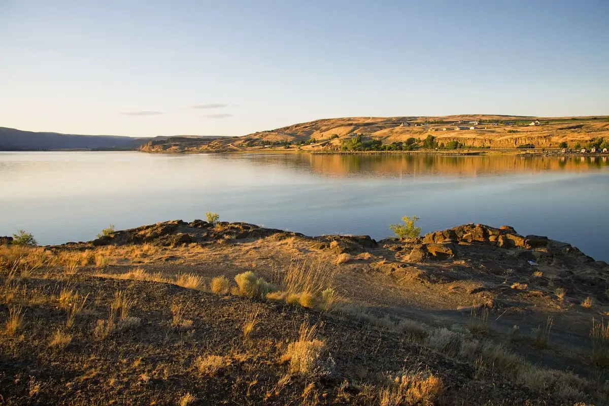 Calm waters of Soap Lake at golden hour seen from its rocky, grassy south shore