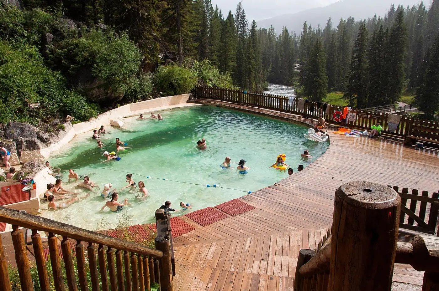 Granite Hot Springs concrete pool with wooden deck surrounded by dense evergreen forest