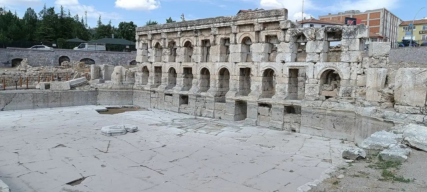 Arched stone facade of the Sarıkaya Roman Bath above its paved marble pool area