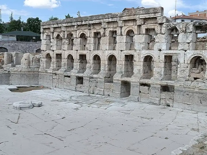 Arched stone facade of the Sarıkaya Roman Bath above its paved marble pool area