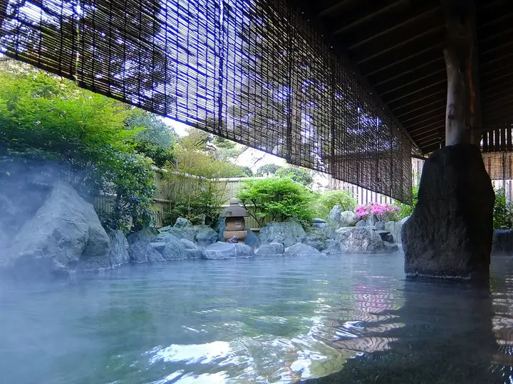 Steaming rock lined open air bath under a bamboo blind at a Tamatsukuri Onsen inn