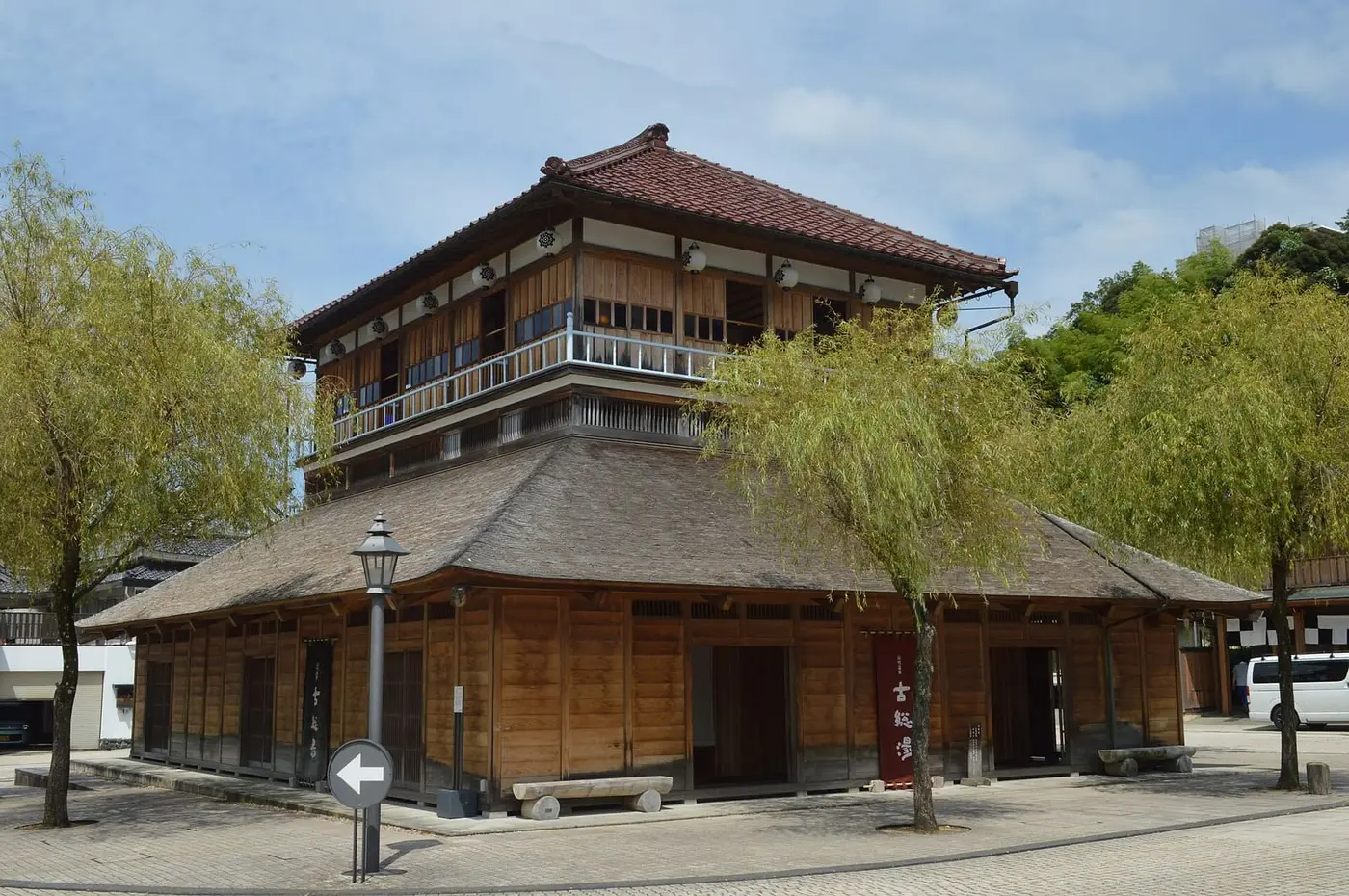 Two storey wooden Kosoyu bathhouse on the square of Yamashiro Onsen with willow trees