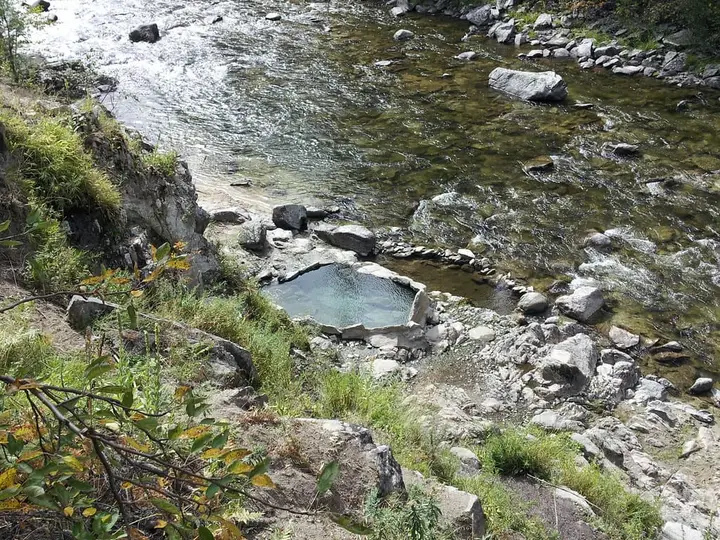 Small rock-lined hot spring pool at Mile 16 Hot Springs on the bank of a clear rocky river