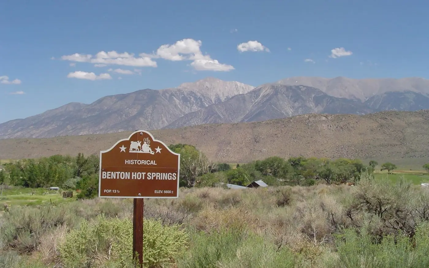 Historical marker sign for Benton Hot Springs in sagebrush below the snowy Eastern Sierra