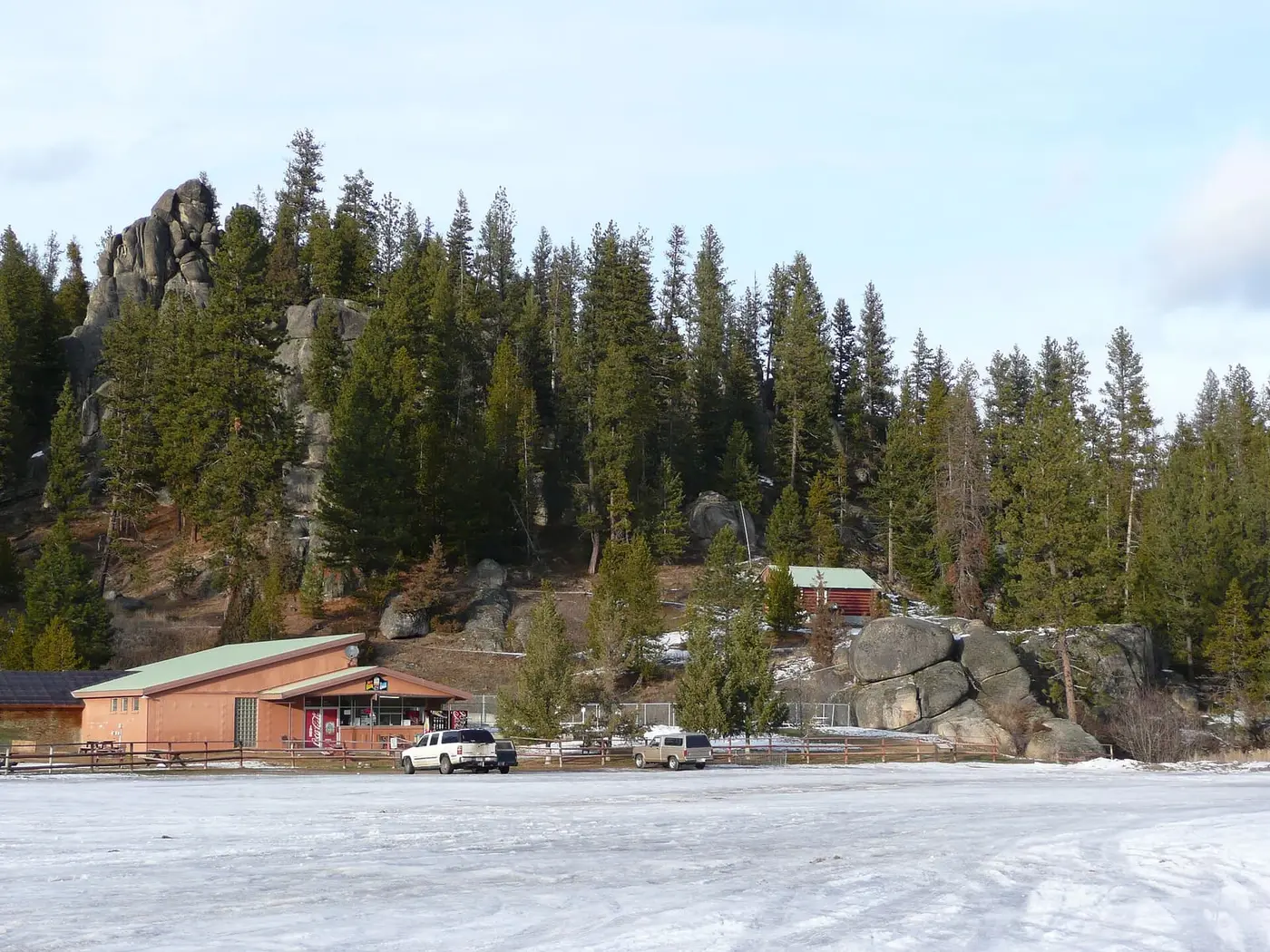 Lolo Hot Springs resort buildings below granite rock outcrops and pine forest on a snowy winter day