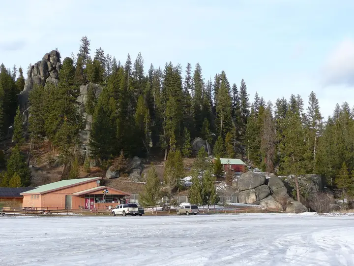 Lolo Hot Springs resort buildings below granite rock outcrops and pine forest on a snowy winter day