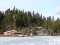 Lolo Hot Springs resort buildings below granite rock outcrops and pine forest on a snowy winter day