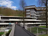Modern spa building of Terme di Comano with a walkway and wooded hills behind