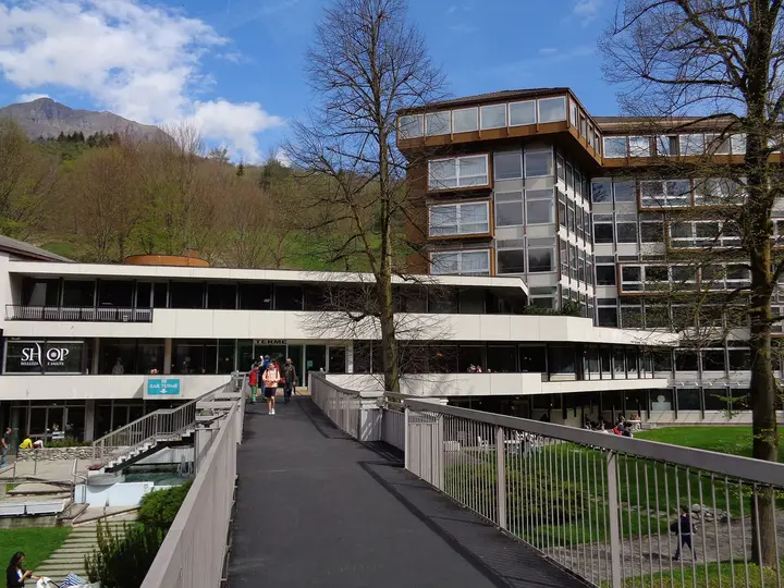 Modern spa building of Terme di Comano with a walkway and wooded hills behind