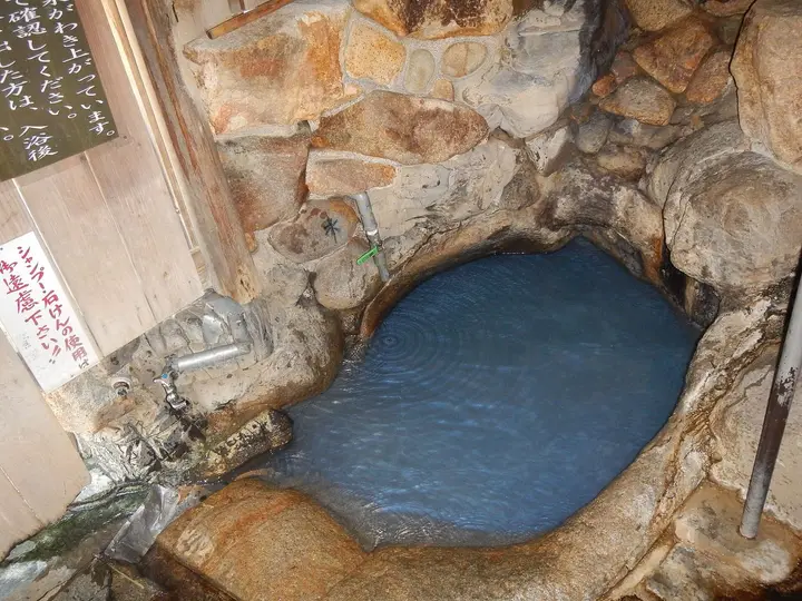 Blue mineral water filling the small rock basin of Tsuboyu at Yunomine Onsen