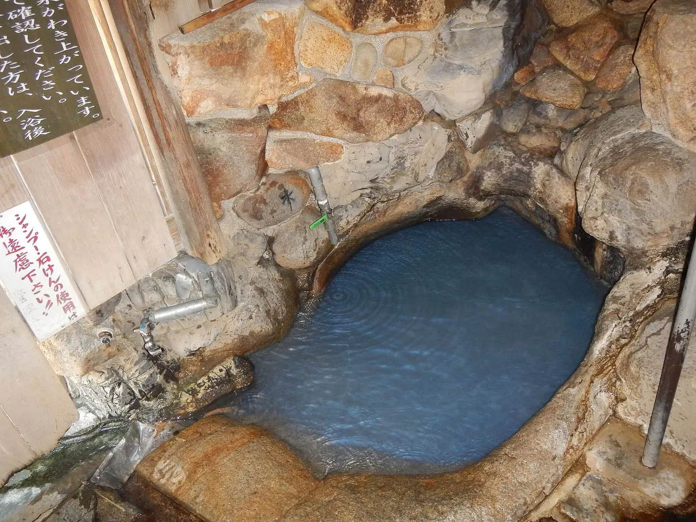 Blue mineral water filling the small rock basin of Tsuboyu at Yunomine Onsen