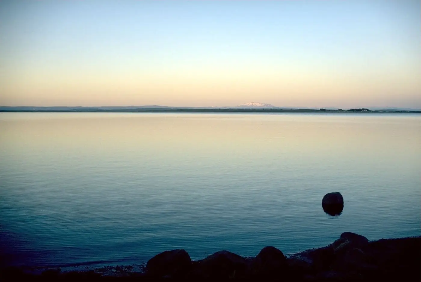 Calm Lake Laugarvatn at dusk with distant mountains on the horizon near Fontana