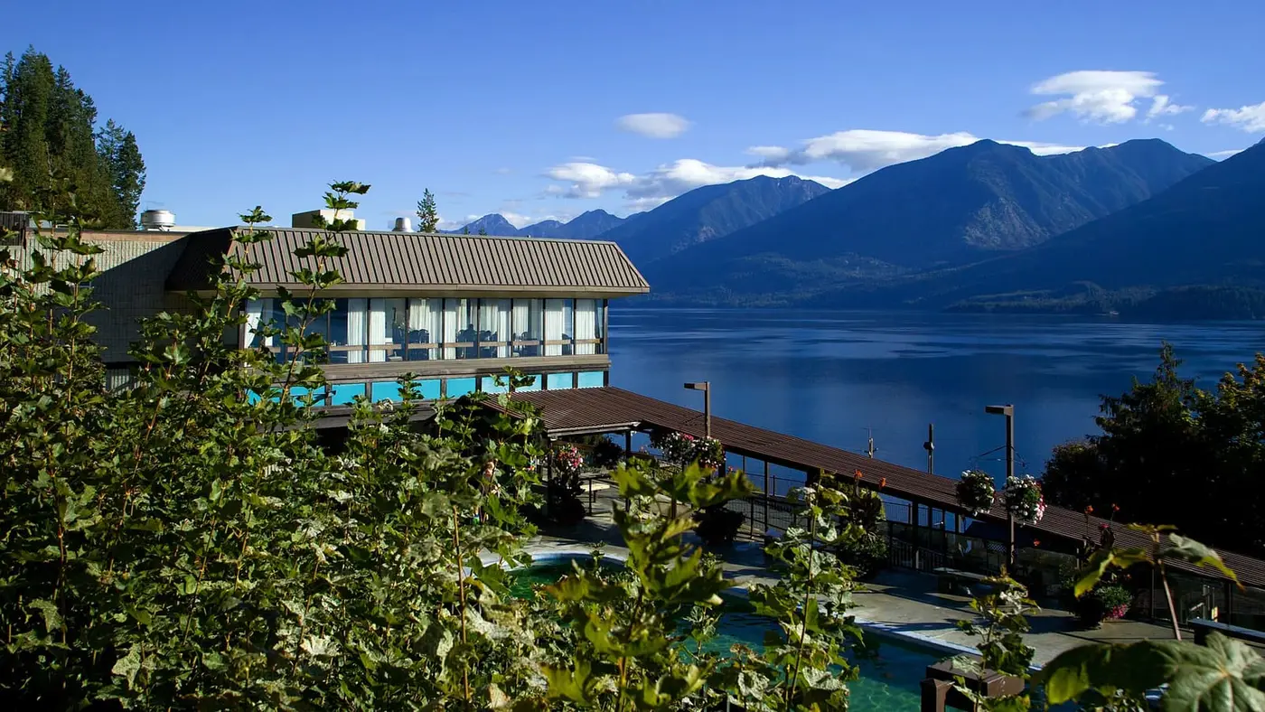 Ainsworth Hot Springs Resort pool below the lodge balcony, with Kootenay Lake and mountains beyond
