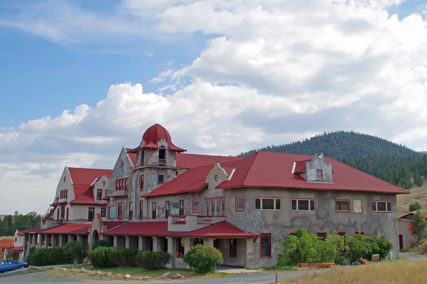 Historic Spanish Mission style Boulder Hot Springs Hotel with red roofs and a cupola under summer clouds
