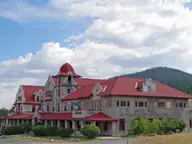 Historic Spanish Mission style Boulder Hot Springs Hotel with red roofs and a cupola under summer clouds