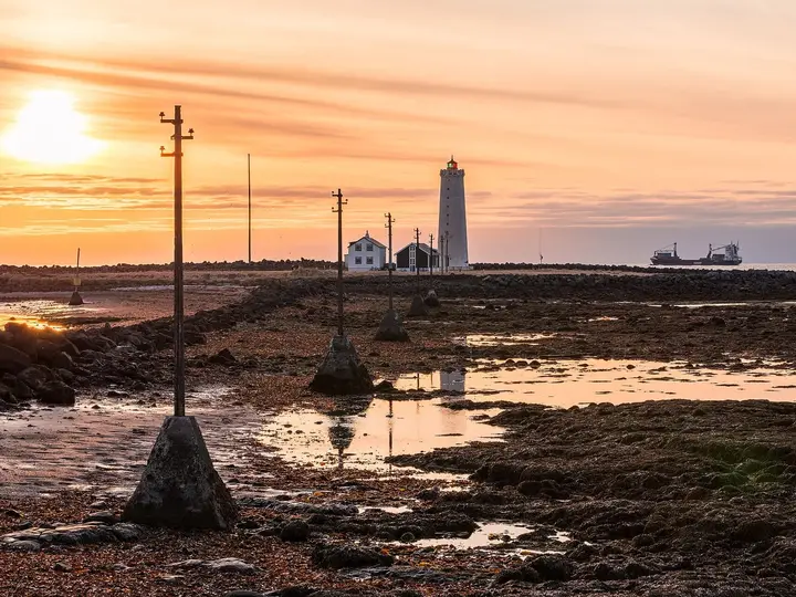 Grótta lighthouse at sunset across the tidal flats of the Seltjarnarnes shore near Kvika