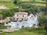 Old stone mill above the white travertine cascades and terraced pools of Cascate del Mulino