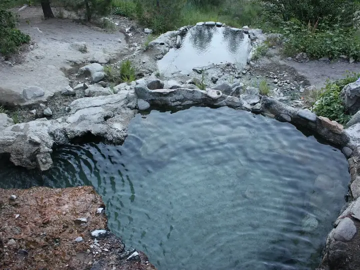Rock-rimmed soaking pool at Loftus Hot Spring with a smaller pool above it on the rocky hillside