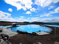 Milky blue geothermal lagoon at Mývatn with wooden decks and lava rocks under a bright sky
