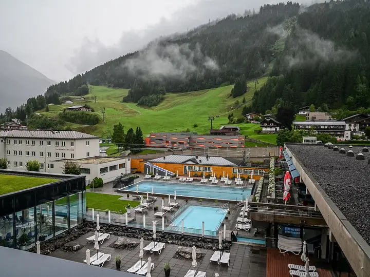 Outdoor thermal pools of the Felsentherme Bad Gastein below misty green mountain slopes