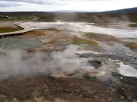 Steaming vents and white sinter crust in the Hveravellir geothermal area with a wooden boardwalk