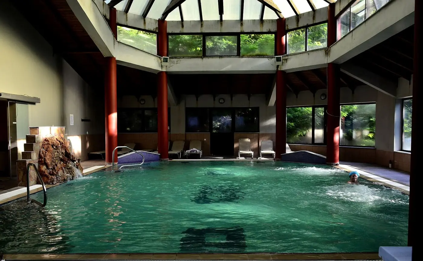 Indoor thermal pool at Loutra Smokovou under a glass roof with red columns