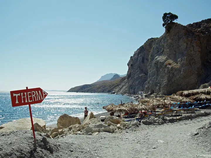 Red Therma sign on the pebble beach below the cliffs of south east Kos