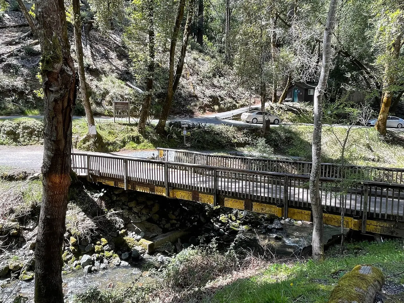 Wooden footbridge over a rocky creek on the wooded grounds of Orr Hot Springs Resort