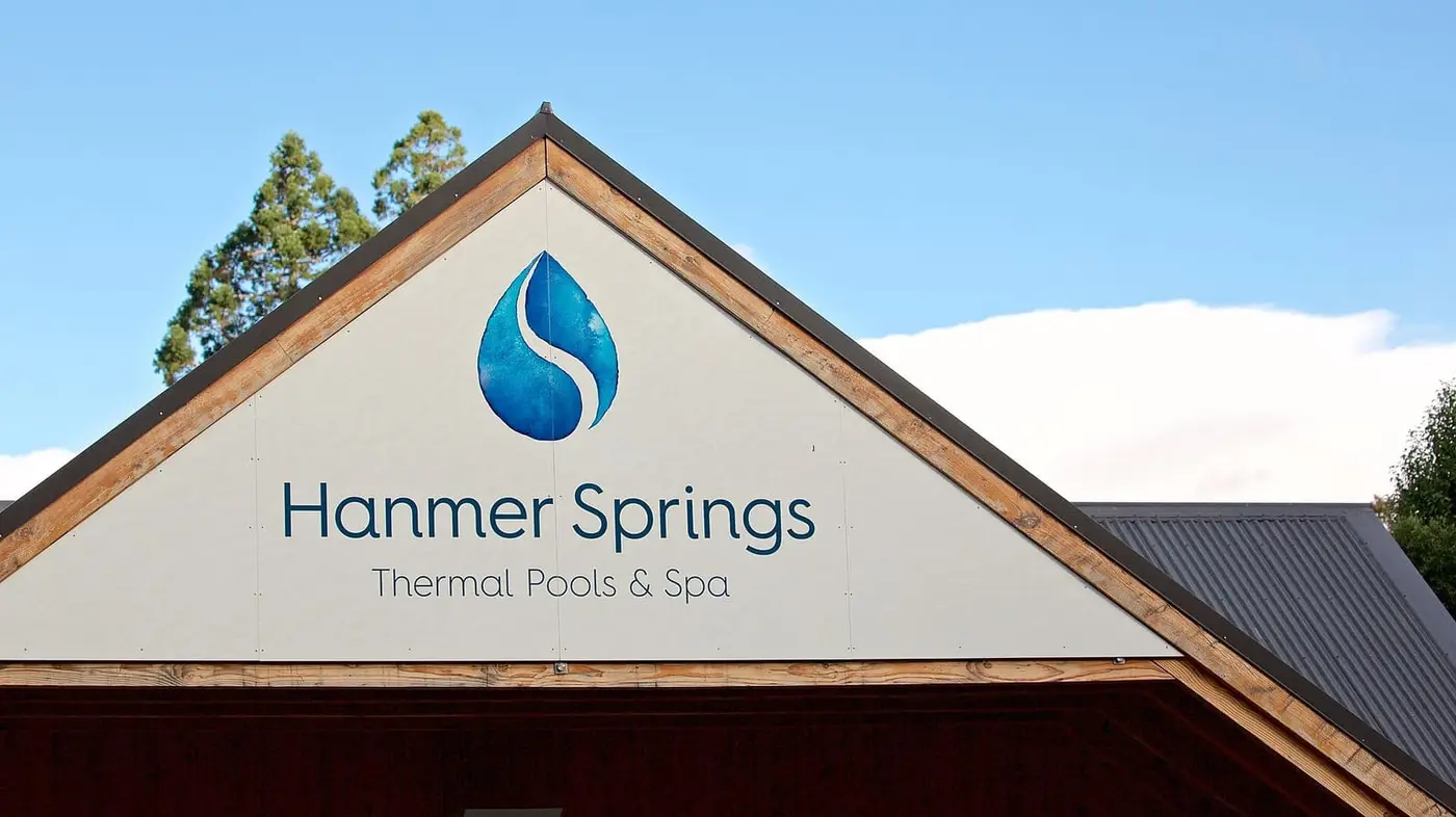 Gabled entrance building with the Hanmer Springs Thermal Pools and Spa sign under blue sky
