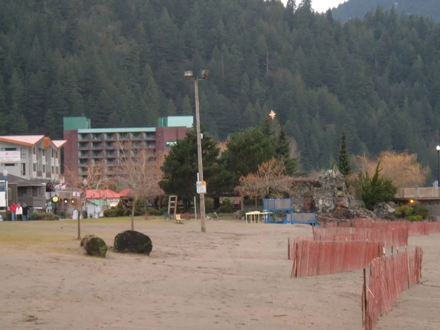 Harrison Hot Springs Resort hotel tower behind the lakeside beach below forested hills