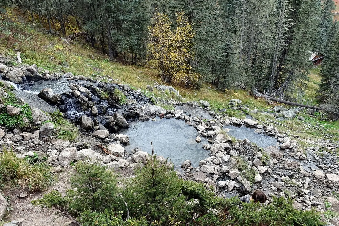 Rock lined pools of San Antonio Hot Springs stepping down a forested hillside with autumn color