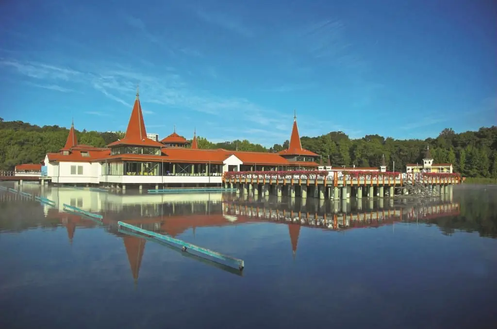 Lake Hévíz bathhouse with red turreted roofs reflected in the calm thermal lake